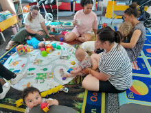Lancaster group, shows parents and baby sat round chatting and playing 